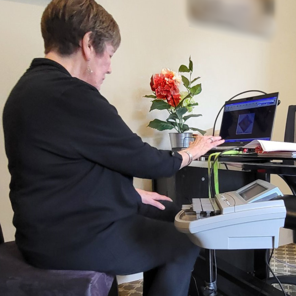 Female seated at desk with laptop and stenography machine_Experienced court reporter